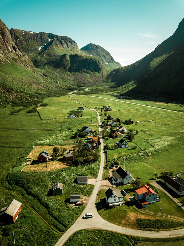 Explore the serene beauty of Lenvik, Norway's lush valleys and charming village from above.